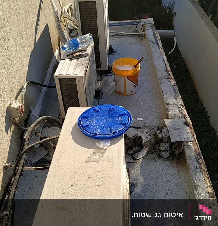 דלי עם חומר איטום ומברשת על גג